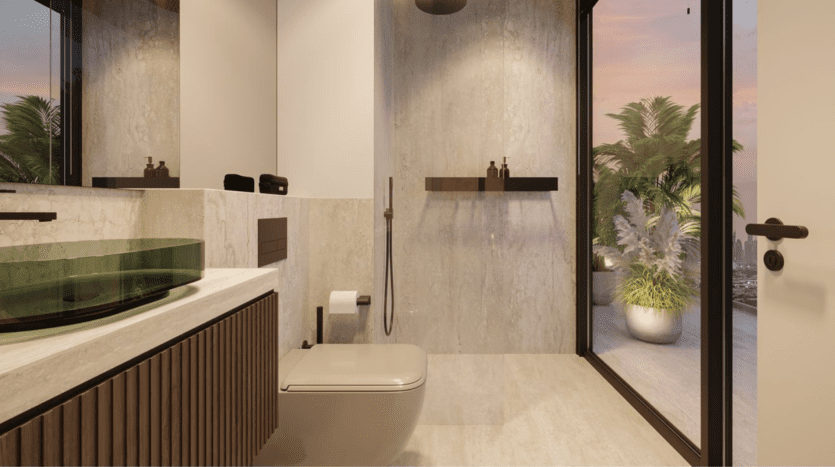 Salle de bains moderne avec toilettes flottantes, lavabo en verre vert, grand miroir, décor minimal et porte vitrée s'ouvrant sur une terrasse avec des plantes en pot au coucher du soleil. Les couleurs neutres et les éléments de design épurés sont omniprésents.