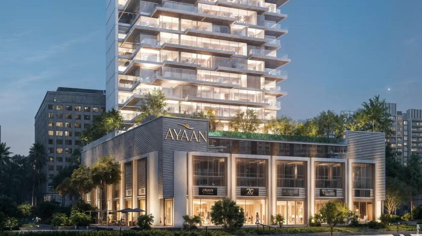 Ayaan Heights 1 by IGO est un immeuble moderne de plusieurs étages baptisé "Ayaan", qui propose des magasins aux étages inférieurs et une tour au-dessus avec des balcons et de la verdure, magnifiquement illuminée le soir.