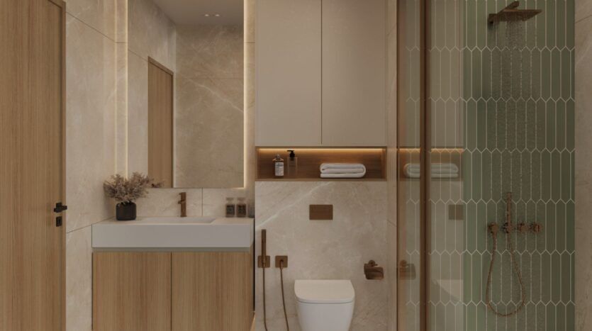 La salle de bains moderne d'Ayaan Heights 1 par IGO comprend des murs en marbre beige, un meuble-lavabo en bois avec évier, des toilettes murales, des étagères avec des serviettes et des objets de décoration, et une douche vitrée avec des carreaux verticaux et des accessoires en bronze.