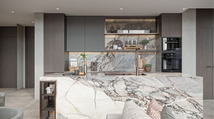 Modern kitchen with marble countertops and backsplashes, elegant dark cabinetry, built-in oven and copper faucet. Open shelving with decorative objects inspired by Sierra by Iman enhance the elegant, contemporary atmosphere in neutral tones.