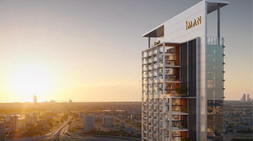 A modern tower with glass balconies and "IMAN" signs rises into the sunset, overlooking a sprawling cityscape - this is Sierra by IMAN, redefining luxury living on a breathtaking urban skyline.