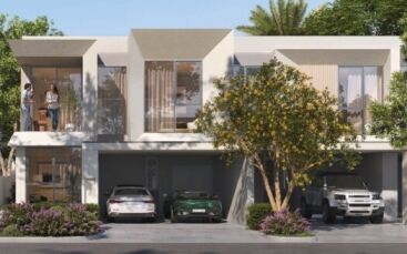 Maison moderne de deux étages avec de grandes fenêtres, des balcons et un garage. Trois voitures sont garées devant la maison et deux personnes se tiennent sur un balcon. Des arbres et des arbustes verdoyants entourent le bâtiment.