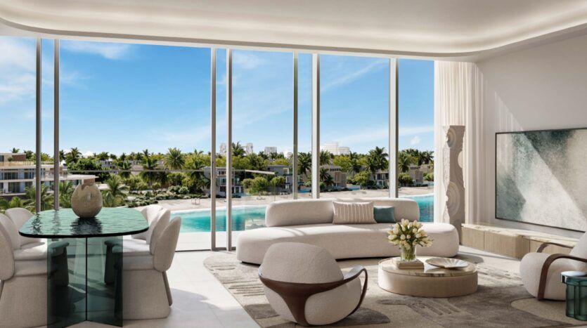 Bright, modern living room at Palm Central with large windows overlooking a tropical pool and palm trees. It features white sofas, round chairs, a glass dining table, abstract artwork and sunlight streaming in.
