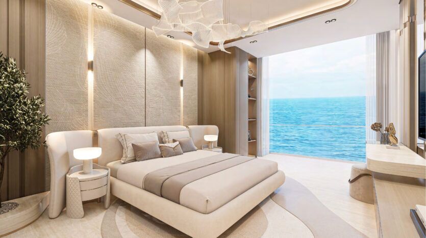La chambre à coucher moderne et élégante dans les tons beige et crème du Breez by Danube Maritime City comprend un grand lit, un éclairage élégant, des fenêtres allant du sol au plafond avec vue sur l'océan, ainsi qu'un bureau, une télévision et une plante en pot pour un luxe serein.
