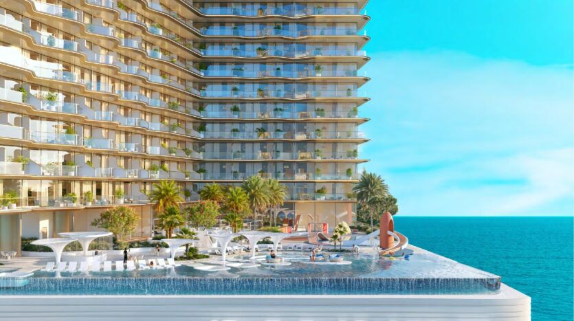 L'immeuble moderne de grande hauteur Breez by Danube Maritime City, avec ses balcons incurvés, donne sur une piscine à débordement, des chaises longues, des palmiers et des jardins paysagers, avec pour toile de fond une mer d'un bleu éclatant et un ciel limpide.