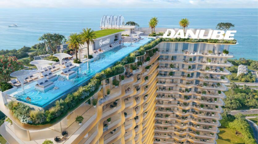 Breez by Danube Maritime City est une tour de luxe qui dispose d'une piscine à débordement sur le toit, de chaises longues, de palmiers et d'une végétation luxuriante surplombant l'océan. Le mot "DANUBE" apparaît en grosses lettres au sommet du bâtiment.