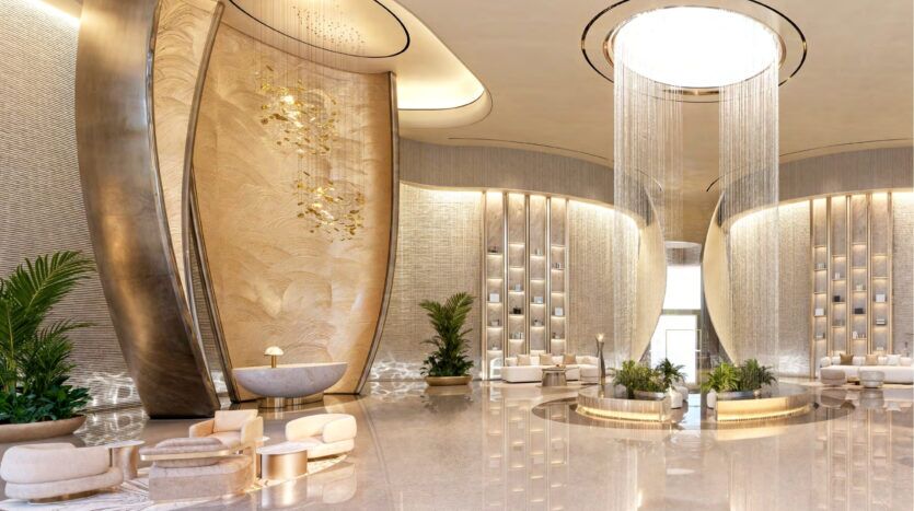 Hall d'entrée luxueux avec de hauts plafonds, un élégant décor or et beige, des éléments muraux incurvés, des sièges modernes et des plantes vertes luxuriantes, qui reflètent l'ambiance sophistiquée du Breez by Danube Maritime City. Un grand lustre circulaire sert de pièce maîtresse.