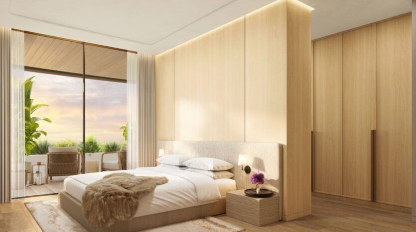 La chambre à coucher moderne et minimaliste de l'Edition est dotée d'un grand lit, de boiseries claires, de tables de chevet et de fenêtres allant du sol au plafond qui s'ouvrent sur un balcon où l'on peut s'asseoir en plein air et admirer la verdure luxuriante au coucher du soleil.