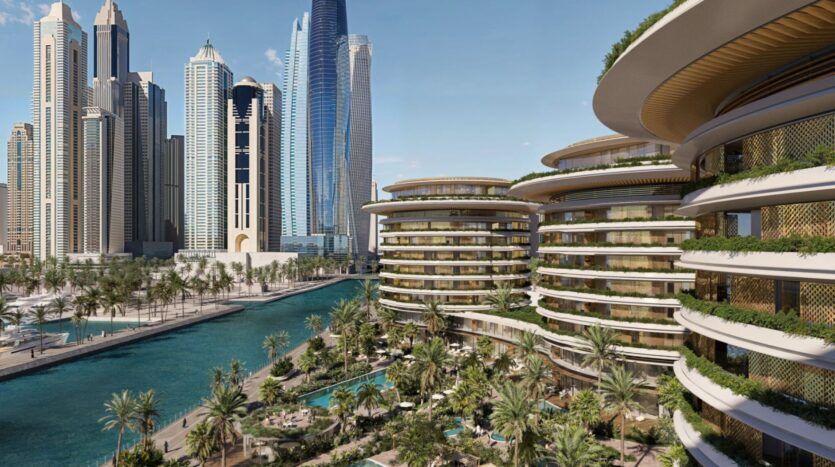 Un paysage urbain moderne présentant les grands gratte-ciel de The Edition et des bâtiments ronds au design unique au bord d'un canal, entourés d'une végétation luxuriante, de palmiers et de piscines sous un ciel bleu clair.