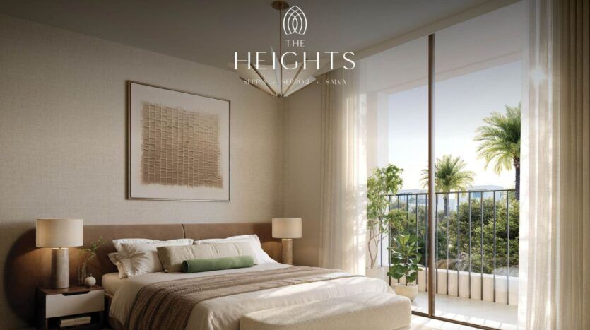 La chambre moderne de l'hôtel The Heights est dotée d'un grand lit, de tables de chevet et d'un décor neutre. Des fenêtres allant du sol au plafond s'ouvrent sur un balcon avec des palmiers et de la verdure. Le logo "The Heights" est affiché en haut de l'image.