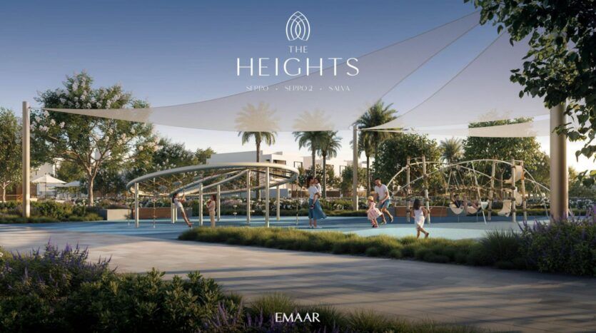 Enfants et adultes profitent d'une aire de jeux moderne avec des structures d'escalade et des voiles d'ombrage, entourée de verdure et de palmiers dans la communauté résidentielle The Heights. Les logos "The Heights" et "EMAAR" sont affichés en haut et en bas.