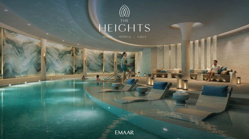 Une luxueuse piscine intérieure à The Heights, avec des chaises longues dans l'eau, des personnes se relaxant au bord de la piscine et des œuvres d'art murales modernes en forme de vagues. La scène tranquille est rehaussée par un éclairage doux et un décor élégant portant la mention "EMAAR".