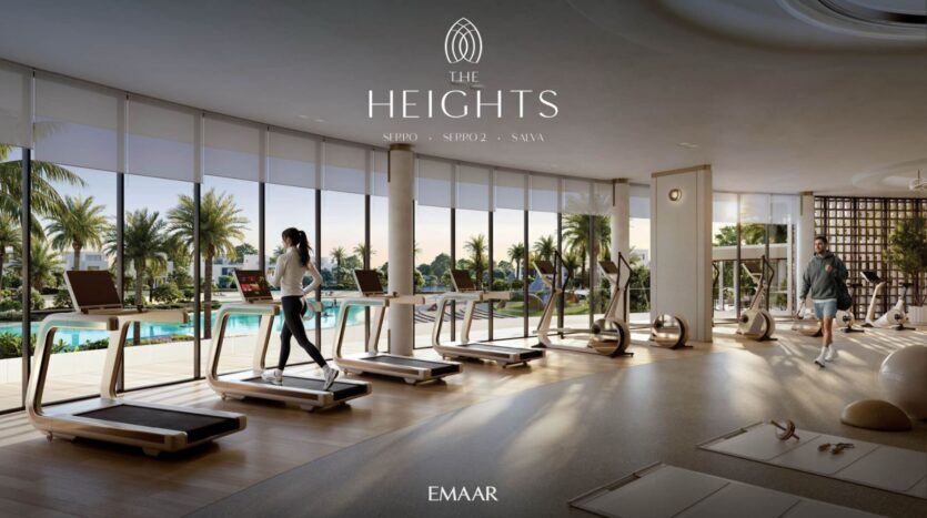 La salle de sport moderne de The Heights est dotée de grandes fenêtres, de tapis roulants et d'appareils de fitness donnant sur une piscine et des palmiers. Deux personnes font de l'exercice à l'intérieur, baignées par la lumière naturelle. Le texte indique "The Heights" et "EMAAR".
