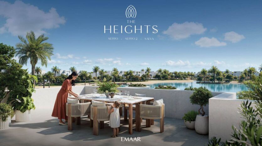 Une femme et un enfant installent une table à manger en plein air sur une terrasse ensoleillée de The Heights, avec vue sur un lac, des palmiers et des maisons modernes. Le ciel bleu clair ajoute à l'atmosphère sereine. Le texte indique "The Heights" et "EMAAR.