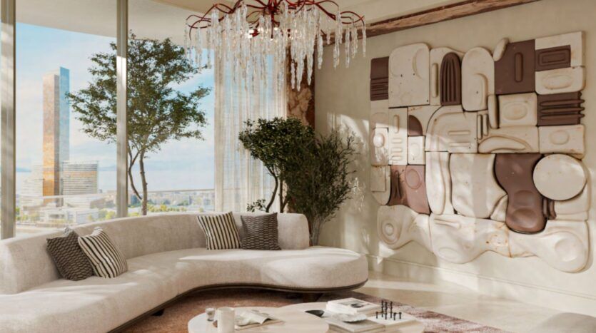 The Château's modern living room features a curved white sofa, striped cushions, a round coffee table, large windows overlooking the city, large indoor plants, a crystal chandelier, and textured abstract wall art.