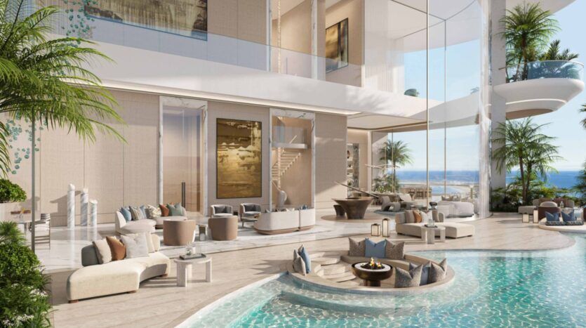 Luxueux espace de vie ouvert dans les résidences Amali, avec un mobilier moderne, une piscine intérieure et un coin salon en contrebas. De grandes fenêtres offrent une vue sur l'océan, tandis que des plantes hautes et des œuvres d'art complètent le décor aéré et élégant.