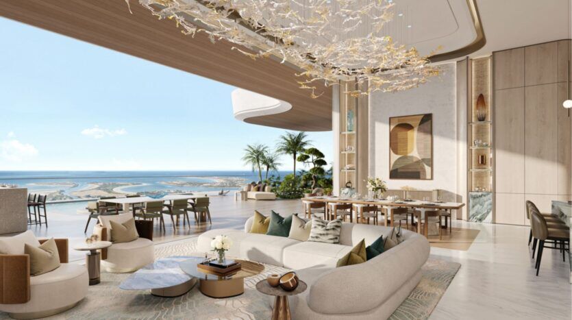 Luxueux salon et salle à manger ouverts des résidences Amali, avec un décor moderne, un grand lustre abstrait, des fenêtres allant du sol au plafond et offrant une vue sur l'océan, un mobilier contemporain, des plantes d'intérieur et des tons neutres dans l'ensemble de l'intérieur spacieux et aéré.
