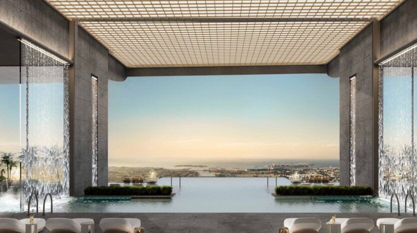La luxueuse piscine intérieure à débordement des résidences Amali est agrémentée de cascades à l'entrée et offre une vue pittoresque sur la ville et le littoral. Des chaises longues modernes bordent l'espace, dont le plafond ouvert est orné d'un quadrillage saisissant.