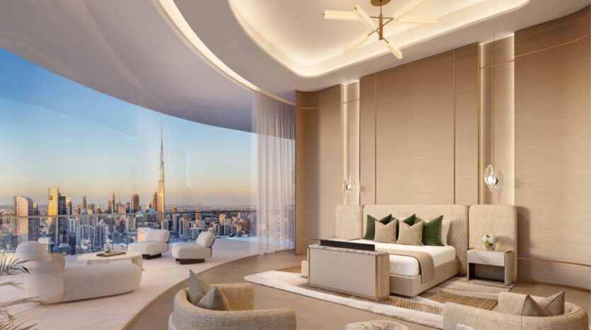 Une chambre luxueuse et moderne dans les résidences Amali, avec un grand lit, un décor beige élégant, des fenêtres allant du sol au plafond, un mobilier contemporain et une vue sur la ville avec le Burj Khalifa au coucher du soleil.