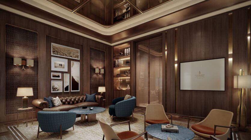 Le luxueux salon de Four Seasons Private Residences présente des murs en bois, des canapés et des chaises modernes, des tables rondes, un éclairage chaleureux, des œuvres d'art encadrées, un écran mural, des étagères encastrées avec des objets de décoration et un haut plafond avec des éclairages encastrés.
