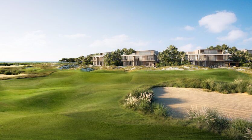 Les villas modernes de Four Seasons Private Residences sont entourées de palmiers et surplombent un terrain de golf luxuriant avec des greens manucurés et un bunker de sable, sous un ciel d'un bleu éclatant avec des nuages épars.