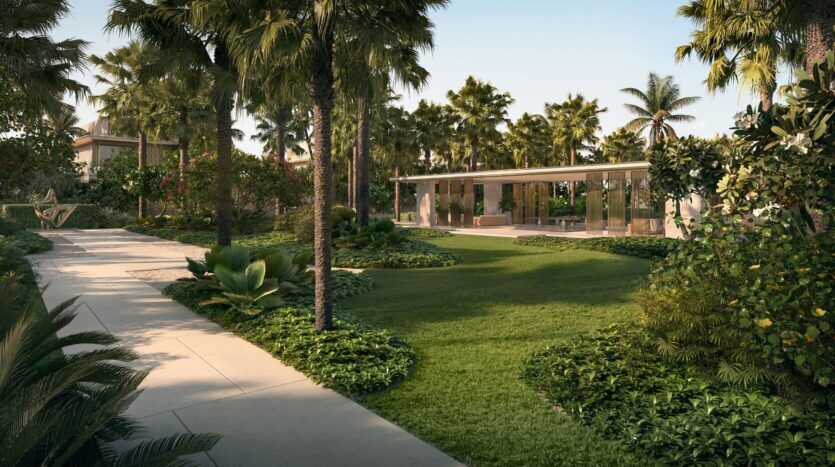 Un jardin tropical luxuriant avec des palmiers, des pelouses entretenues et des arbustes entoure les résidences privées Four Seasons. La lumière du soleil filtre à travers la verdure le long d'une allée pavée sinueuse, menant à un bâtiment moderne aux murs de verre à l'arrière-plan.