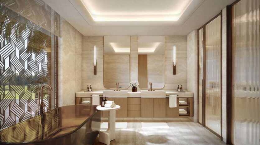 Luxueuse salle de bains moderne à Four Seasons Private Residences comprenant une baignoire foncée autoportante, deux lavabos, de grands miroirs, un éclairage doux, des murs en pierre beige et des panneaux de verre décoratifs. Une petite table blanche et des serviettes sont soigneusement disposées.