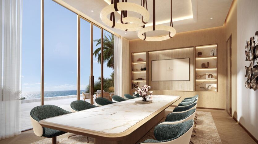 La salle de conférence moderne de Four Seasons Private Residences est équipée d'une table en marbre, de chaises sarcelles, d'étagères encastrées, de grandes fenêtres avec vue sur l'océan et de lampes suspendues circulaires accrochées au plafond.