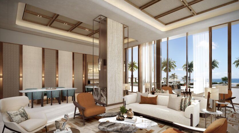 Le salon luxueux et moderne de l'hôtel Four Seasons Private Residences comprend des canapés et des fauteuils élégants, ainsi que des tables en marbre. De grandes fenêtres laissent entrevoir des palmiers et une vue sur l'océan, tandis qu'un éclairage doux et des tons neutres créent une atmosphère sereine et accueillante.