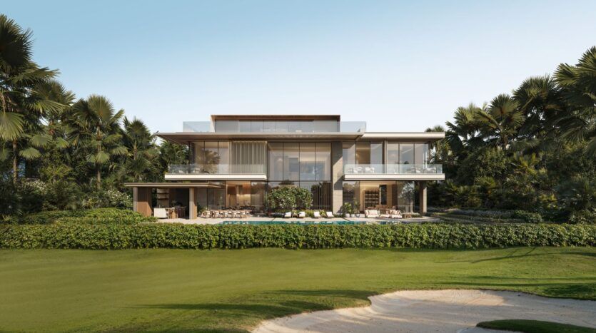 La maison moderne de deux étages, entourée d'arbres et d'une végétation luxuriante, est dotée d'une piscine et d'un espace de détente extérieur, rappelant les résidences privées Four Seasons, face à une pelouse entretenue et à un bunker de sable, sous un ciel bleu clair.
