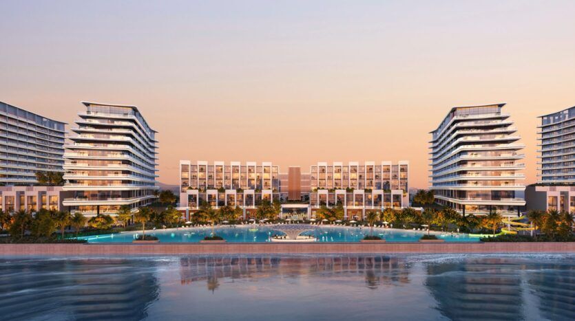 Complexe moderne au bord de l'eau, River Cove Residences, avec des bâtiments à plusieurs étages, des palmiers et une piscine d'un bleu limpide au coucher du soleil. Les bâtiments se reflètent sur l'eau tandis que le ciel s'illumine de tons chauds orange et roses.