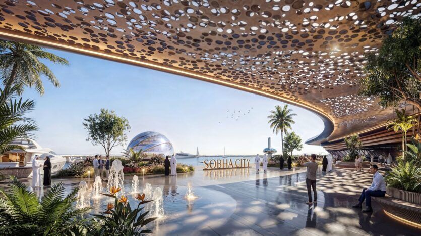 Une place futuriste au bord de l'eau avec un auvent perforé, des palmiers, des jeux d'eau, des gens qui marchent et un dôme métallique près de la mer évoque l'élégance des résidences River Cove. L'enseigne indique "SOBHA CITY" sous un ciel bleu limpide.