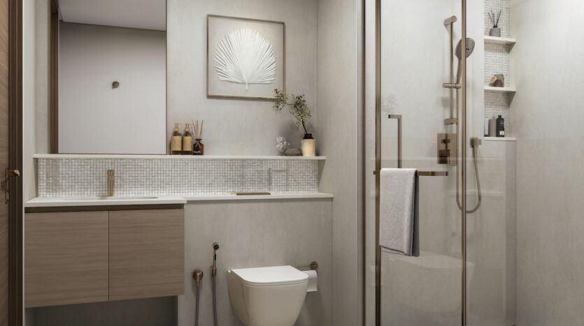 La salle de bains moderne de River Cove Residences présente des murs beige clair, un meuble-lavabo en bois flottant, des toilettes murales et une douche en verre. Des accessoires minimalistes et des feuilles d'art encadrées complètent cet espace serein.