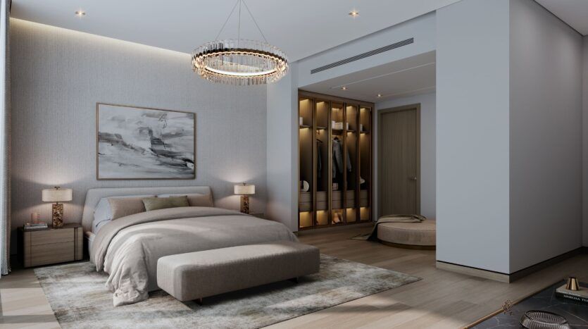 A modern bedroom at The Orchard by Sobha featuring a king-size bed, neutral bedding, and an upholstered bench at the foot of the bed. A lighted closet, abstract wall art, an elegant chandelier, and soft lighting create a comfortable and sophisticated atmosphere.