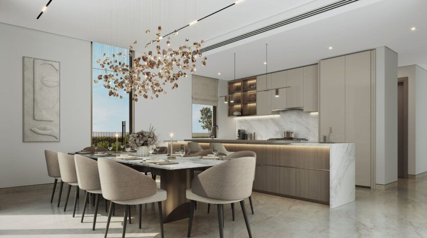 The modern dining room and kitchen at The Orchard by Sobha, featuring a marble island, sleek furniture, a large table for eight, elegant beige chairs, a sculptural gold chandelier, and minimalist wall art—all in neutral tones and bathed in natural light.
