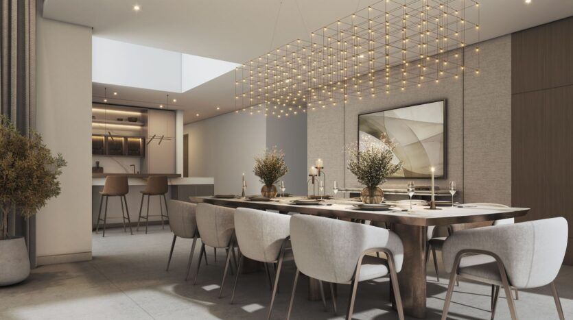 A modern dining room featuring a large wooden table, white upholstered chairs, minimalist decor, and a grid-shaped chandelier. The neutral-toned walls complete the look, while the kitchen, with its bar stools, reflects the signature elegance of The Orchard by Sobha.