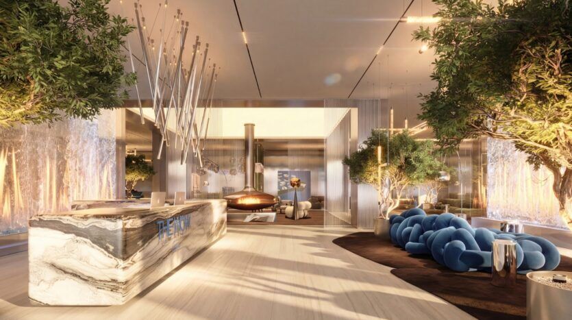 The modern lobby of The Wow Tower hotel features a marble reception desk, artistic lighting, blue velvet seating, lush indoor plants, and warm ambient lighting. Sleek, contemporary design elements create a welcoming atmosphere.