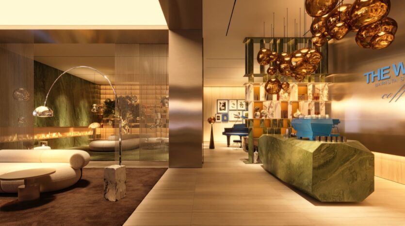 A modern, luxurious lounge in the Wow Tower featuring golden lighting, green marble surfaces, a blue piano, abstract artwork, and plush seating. Glass partitions and sculptural lighting create an elegant and sophisticated atmosphere.