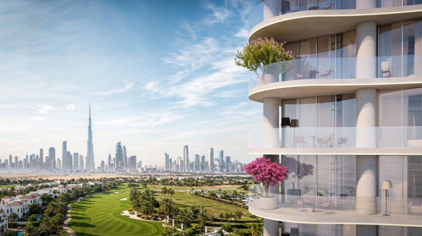 The modern balcony of The Wow Tower, with its glass railings and potted plants, overlooks a golf course and the Dubai skyline—including the Burj Khalifa—under a blue sky dotted with scattered clouds.