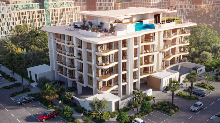Calisi by Zoya est un immeuble moderne de plusieurs étages avec de grands balcons, une piscine sur le toit et un aménagement paysager luxuriant. Des voitures sont garées autour de l'immeuble, tandis que les gratte-ciel voisins sont visibles à l'arrière-plan.