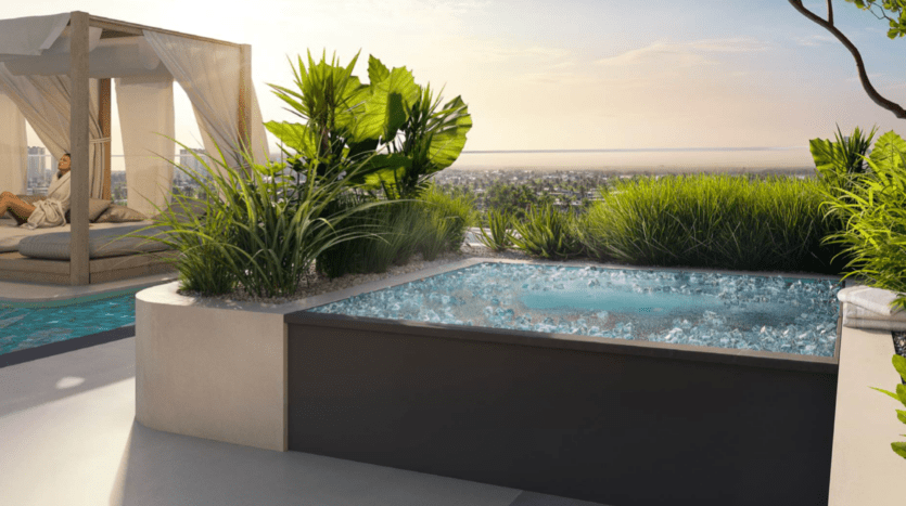 Un spa sur le toit avec un bain bouillonnant Cybele by Wadan entouré de plantes vertes luxuriantes, à côté d'une cabane au bord de la piscine où une personne en peignoir se détend, avec vue sur un paysage urbain au coucher du soleil.