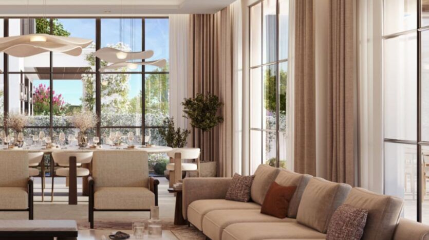 Le salon et la salle à manger modernes de Hudayriyat Golf Estates sont dotés de grandes fenêtres, de canapés, de fauteuils et de rideaux de couleur neutre. La lumière du soleil envahit la pièce, mettant en valeur la table à manger et la verdure du patio.