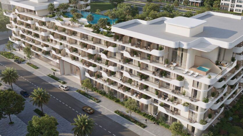 Oxford Cove by Iman est un immeuble d'appartements moderne, blanc, à plusieurs étages, avec des balcons incurvés, de la verdure sur les toits et une piscine privée sur un balcon. Il donne sur une rue bordée d'arbres et de palmiers, avec une piscine en arrière-plan.