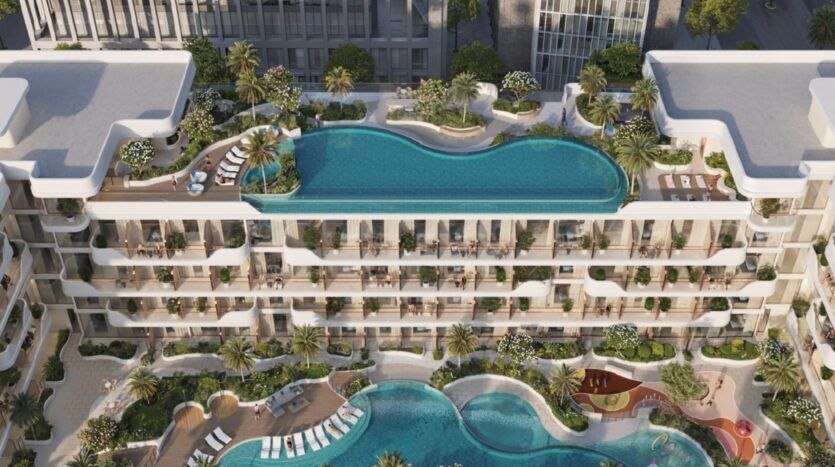 Vue aérienne d'Oxford Cove by Iman, un complexe moderne d'appartements de luxe comprenant des piscines à débordement sur les toits, de multiples balcons, une végétation luxuriante et des espaces extérieurs aménagés avec des chaises longues et une piscine incurvée au niveau du sol.