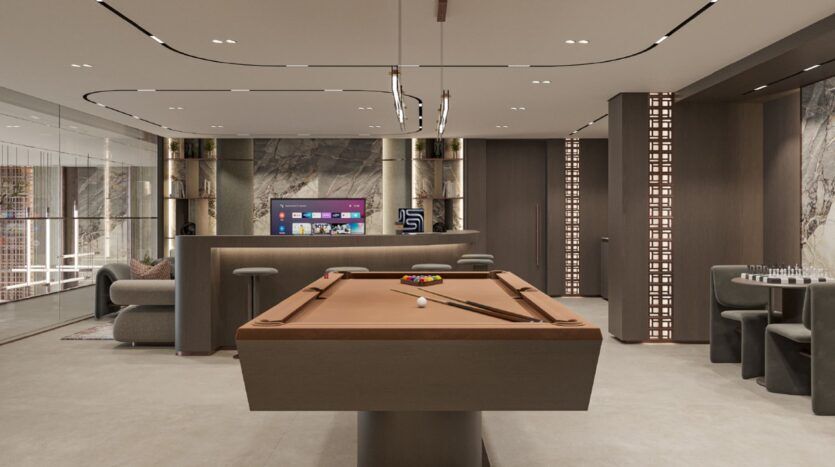 Salle de jeux moderne à Oxford Cove par Iman, avec une table de billard marron au centre, des sièges, une télévision sur le mur du fond, un éclairage contemporain et une table d'échecs dans le coin, le tout dans un décor épuré et des couleurs neutres.