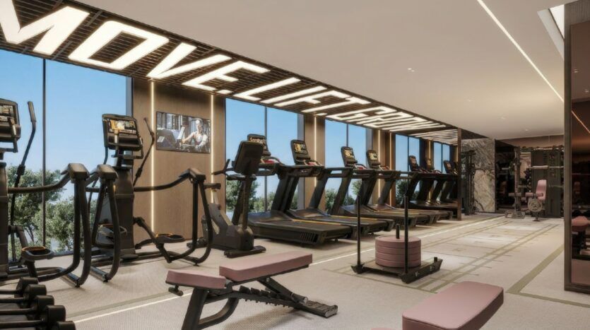 Salle de sport moderne à Oxford Cove par Iman avec des tapis de course, des machines elliptiques et des bancs de musculation. De grandes fenêtres apportent de la lumière naturelle et un panneau de motivation indiquant "MOVE LIFT GROW" (bougez, soulevez, grandissez) est affiché au-dessus de l'équipement.