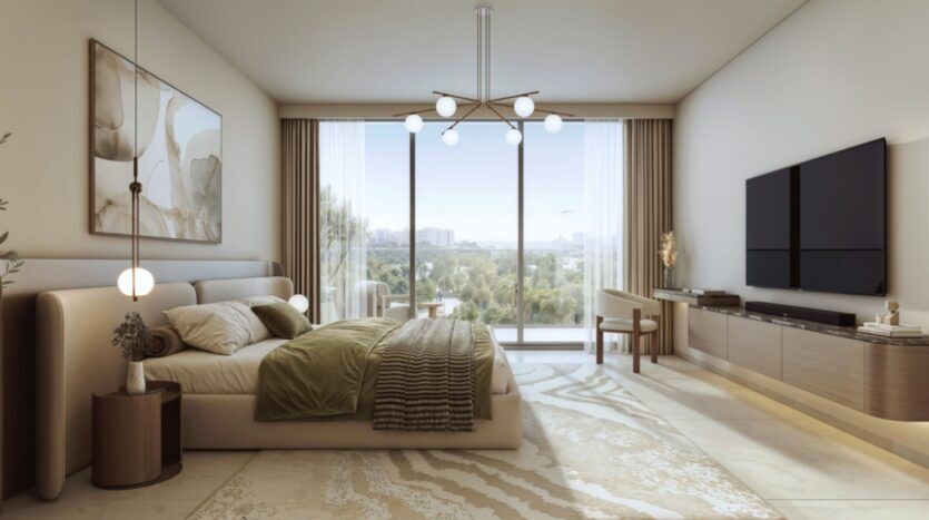 La chambre à coucher moderne et spacieuse de Rotana Residences comprend un grand lit avec une literie verte et beige, des œuvres d'art abstraites, des fenêtres allant du sol au plafond avec vue sur la ville, un lustre élégant, une télévision et un mobilier minimaliste.