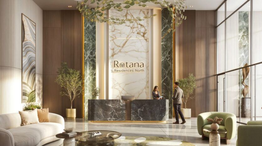 Hall d'entrée d'un hôtel moderne avec de hauts plafonds, d'élégants murs en marbre et un panneau "Rotana Residences North" derrière un bureau de réception en marbre noir. Deux personnes interagissent à la réception, entourées de plantes et de sièges élégants dans cet espace lumineux des Résidences Rotana.