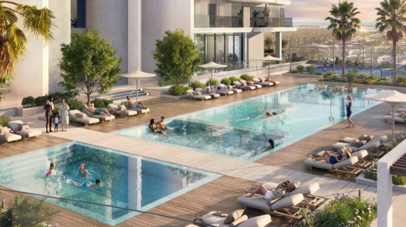 Piscine extérieure moderne des résidences Rotana avec deux bassins, des chaises longues, des gens qui nagent, prennent un bain de soleil et se détendent. Une végétation luxuriante, des palmiers et des vues lointaines sur l'océan ou la baie complètent cette oasis accueillante.