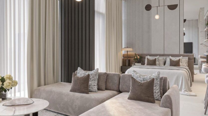 Chambre à coucher moderne composée d'un canapé sectionnel beige, de coussins d'appoint gris et bruns et d'une table basse ronde blanche ; Tresora de Wadan accentue l'espace, tandis que de hautes fenêtres avec des rideaux superposés remplissent la pièce de lumière naturelle.
